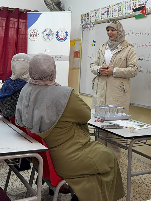 Head shot of woman speaking to two other women in a classroom in Jordan